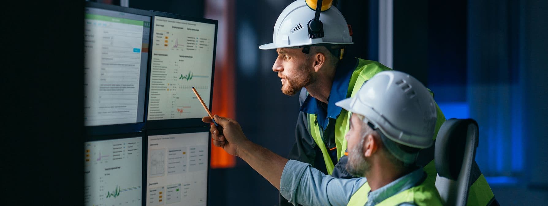 Two engineers monitoring site remotely on 4 various screens