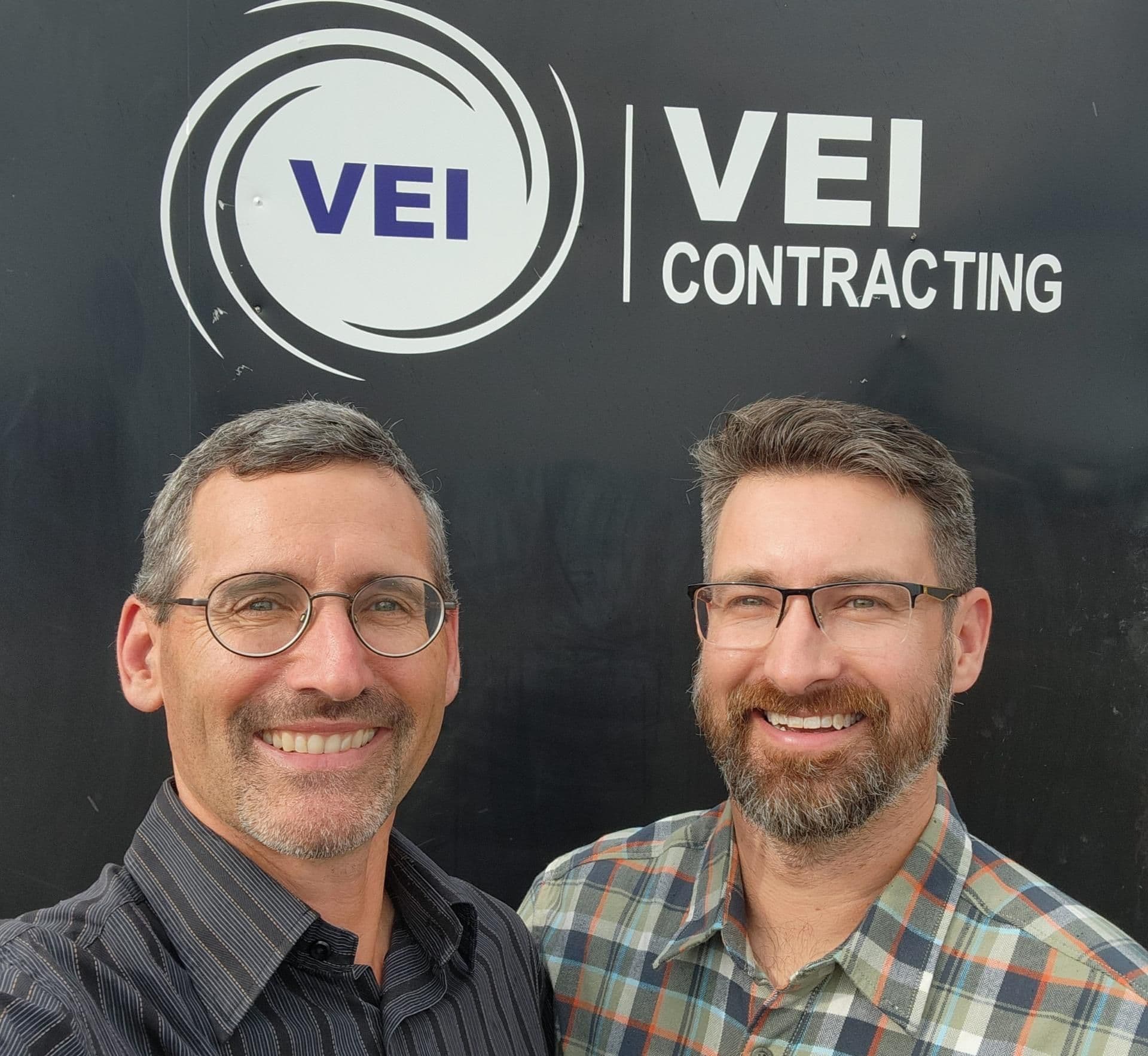 Bruce Tunnicliffe and Steven Reichheld posing together against the backdrop with VEI Contracting logo